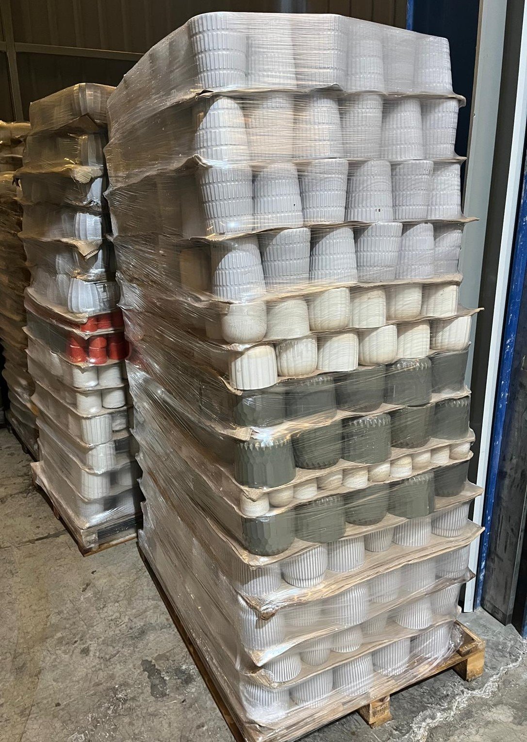 Pallets of glazed stoneware flowerpots stacked in warehouse